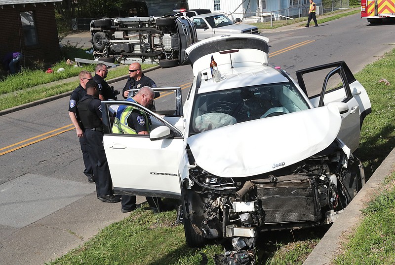 Hot Springs police search a Jeep Compass after its juvenile driver was involved in a rollover wreck with a Chevrolet pickup truck at West Belding and Oakcliff streets shortly before 10 a.m. Friday. - Photo by Richard Rasmussen of The Sentinel-Record