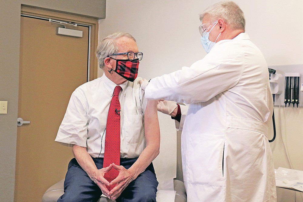 FILE - In this Tuesday, Feb. 2, 2021 photo provided by the Ohio Governor's Office, Gov. Mike DeWine, left, gets his first dose of the COVID-19 vaccine from Dr. Kevin Sharrett, in Jamestown, Ohio. On Friday, April 9, 2021, The Associated Press reported on stories circulating online incorrectly asserting masks are no longer mandatory in Ohio, and DeWine isn’t saying a word about it. But masks remain mandatory in Ohio in indoor spaces as well as outdoors when social distancing is not possible. Ohio rescinded its previous coronavirus health orders on April 5, but the state issued a new order the same day simplifying the guidelines. (Ohio Governor's Office via AP)