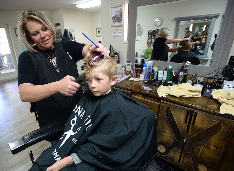 Oxford Haney, 7, sits in a barber chair April 2 as Rebecca Connor, owner of RC√ïs Hair Shop and Tanning, cuts his hair in the shop in Farmington. Go to nwaonline.com/210412Daily/ for today's photo gallery. 
(NWA Democrat-Gazette/Andy Shupe)