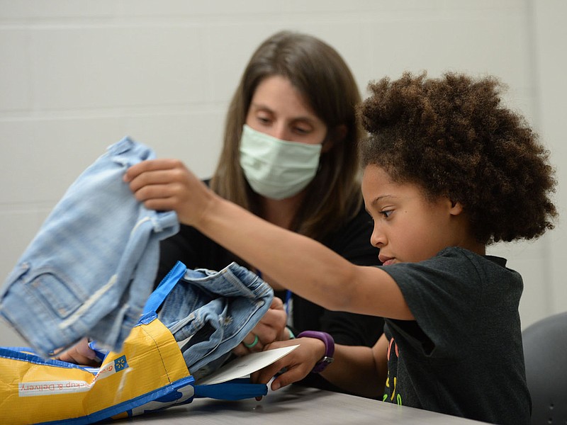 Kamryn Gardner, 7, a first-grader at Evening Star Elementary School in Bentonville, shows the bag of jeans she received from Old Navy Wednesday, April 7, 2021, as her mother, Kim Gardner, watches at the school. Kamryn wrote a letter to Old Navy about the lack of working pockets on girl√ïs jeans. They responded by sending her several pairs with pockets she can use. Visit nwaonline.com/210408Daily/ for today's photo gallery. 
(NWA Democrat-Gazette/Andy Shupe)