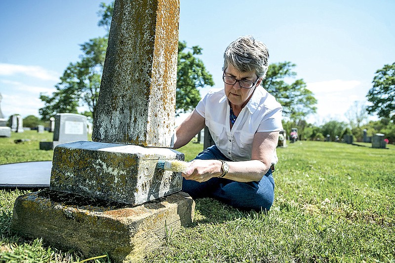 NWA Democrat-Gazette/ANTHONY REYES • @NWATONYR
Abby Burnett, author, cleans some of the dirt of grime off a tombstone Tuesday, April 21, 2015 at Bluff Cemetery in Springdale.