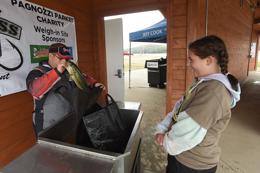 Shannan Moseley weighs a bass for Ava Haymond, 12. Ava placed third in the youth division. She fished with her dad, Lane Haymond.
(NWA Democrat-Gazette/Flip Putthoff)