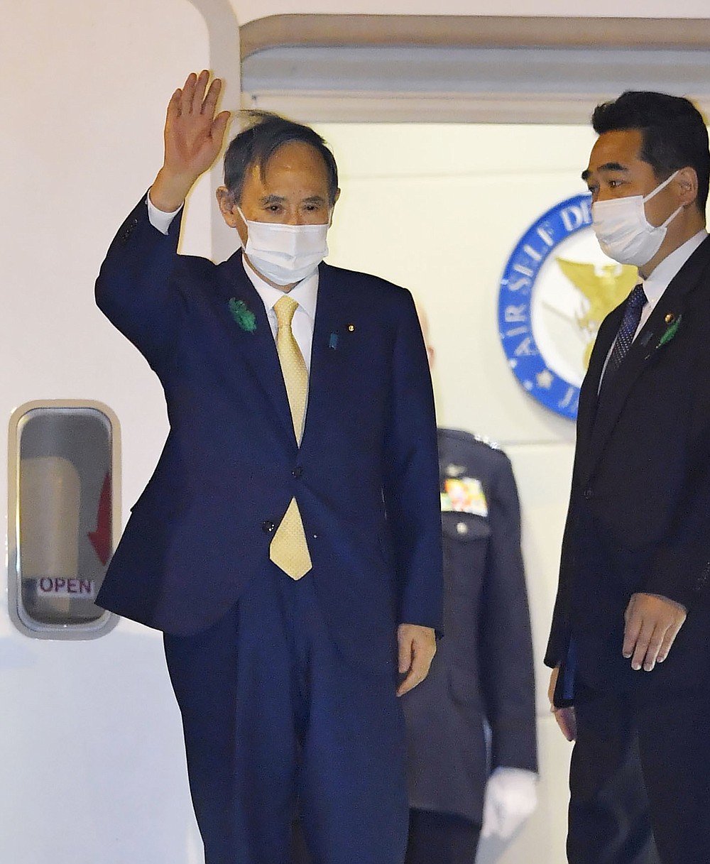 Japanese Prime Minister Yoshihide Suga waves on his departure for the U.S., at Haneda airport, in Tokyo Thursday, April 15, 2021. Suga headed to Washington on Thursday to become a first foreign leader to have a face-to-face meeting with President Joe Biden for talks that would reaffirm the strength of their alliance and how to deal with China's growing assertiveness and challenge to democratic values. (Kyodo News via AP)