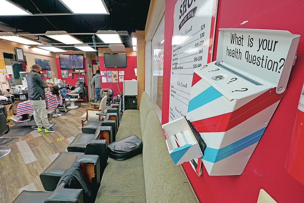 A box encouraging barber shop patrons to submit health questions is displayed at The Shop, Friday, April 9, 2021, in Hyattsville, Md. Barbers are member of the Health Advocates In Reach & Research (HAIR) program, which helps barbers and hair stylists to get certified to talk to community members about health. During the COVID-19 pandemic, a team of certified barbers have been providing factual information to customers about vaccines, a topic that historically has not been trusted by members of black communities because of the health abuse the race has endured over the years. (AP Photo/Julio Cortez)