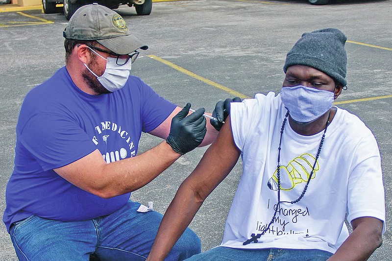 In this April 7, 2021, photo provided by Neighborhood Health, Dr. Pete Cathcart vaccinates Deng Autiak in Nashville. With vaccine supplies increasing in the U.S., the shots are finally reaching thousands of Americans who are homeless. In Nashville, many organizations have set a goal of bringing vaccine to everyone experiencing homelessness by Memorial Day. (Jeremy McCraw/Neighborhood Health via AP)