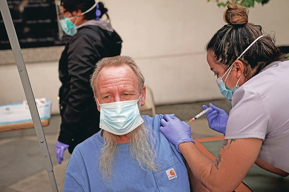 FILE - In this Feb. 3, 2021, file photo, EMT Rachel Bryant, right, administers a COVID-19 vaccine to a homeless man in the courtyard of the Midnight Mission in Los Angeles. Homeless Americans who have been left off priority lists for coronavirus vaccinations β or even bumped aside as states shifted eligibility to older age groups β are finally getting their shots as vaccine supplies increase. (AP Photo/Jae C. Hong)