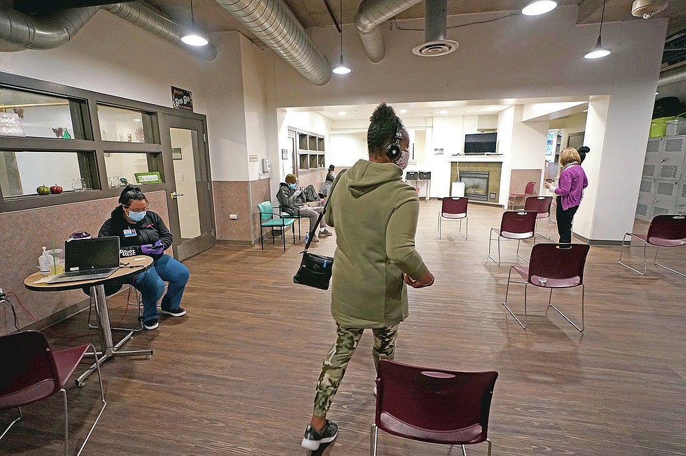 Cidney Oliver, center, walks through an area being used for a COVID-19 vaccination clinic Wednesday, April 7, 2021, at a YWCA shelter for women lacking housing in Seattle where she is staying. Earlier in the day, Oliver received the first dose of the Moderna COVID-19 vaccine at the clinic, which is staffed by workers from Harborview Medical Center. Homeless Americans who have been left off priority lists for coronavirus vaccinations β or even bumped aside as states shifted eligibility to older age groups β are finally getting their shots as vaccine supplies increase. (AP Photo/Ted S. Warren)
