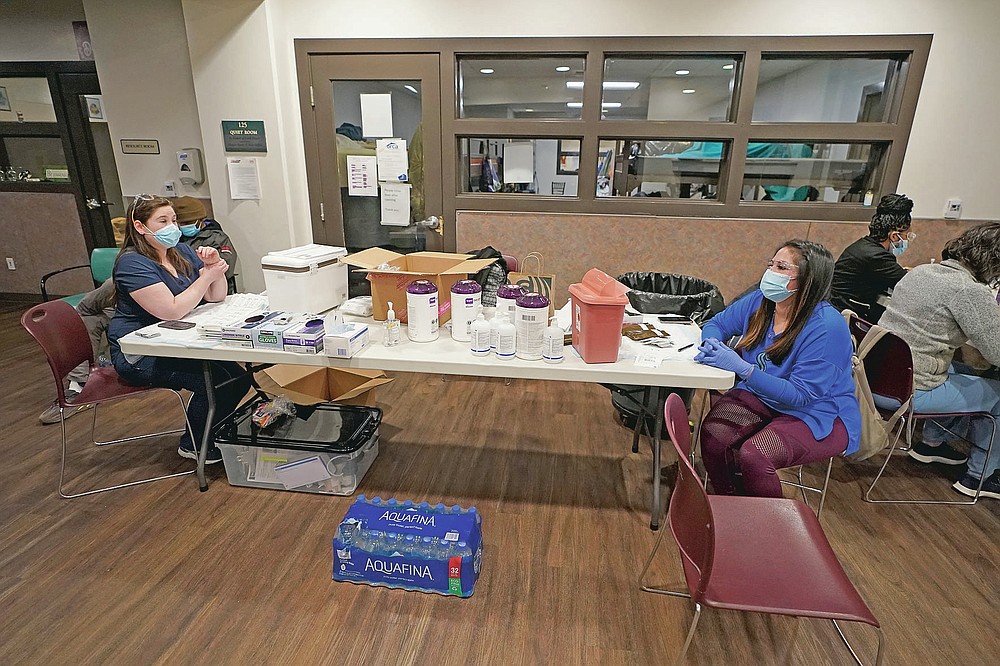 Aurora Artman, right, a medical assistant at Harborview Medical Center, talks with a colleague as they work Wednesday, April 7, 2021, at a COVID-19 vaccination clinic set up at a YWCA shelter for women lacking housing in Seattle. Homeless Americans who have been left off priority lists for coronavirus vaccinations β or even bumped aside as states shifted eligibility to older age groups β are finally getting their shots as vaccine supplies increase. (AP Photo/Ted S. Warren)