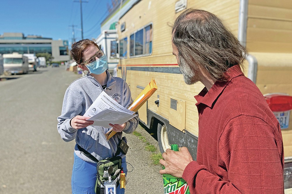 Moira Andrews, a street outreach nurse for Neighborcare Health, speaks with Shane Pisson, 48, who lives in an encampment in the Georgetown neighborhood of Seattle on Monday, April 12, 2021. Andrews spoke with Pisson about the COVID-19 vaccines and answered questions in an effort to vaccinate people experiencing homelessness. Advocates say homeless people are at greater risk of being infected and greater risk of hospitalization and death than the average person, and they should have been prioritized earlier. (AP Photo/Manuel Valdes)