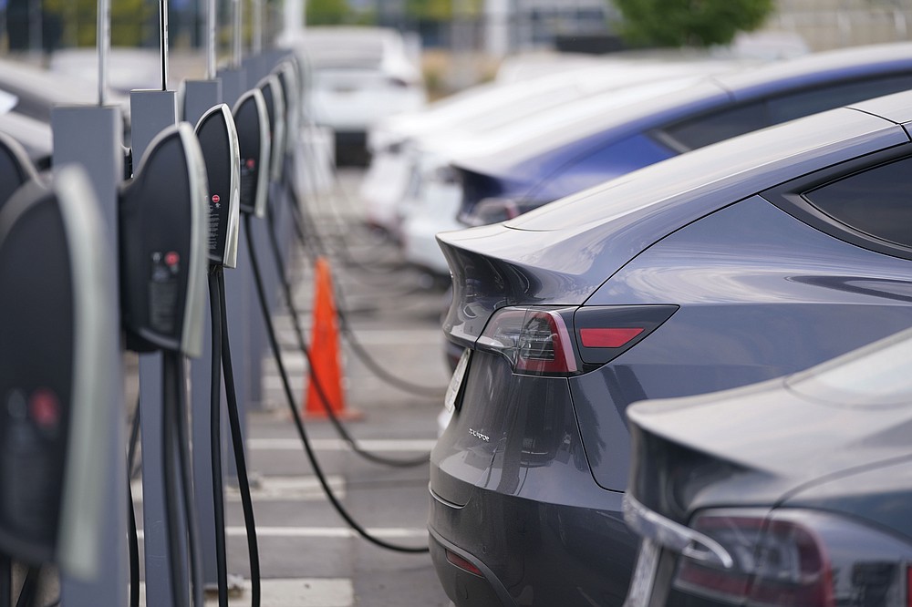 This Aug. 23, 2020 photo shows a long line of unsold 2020 models charge outside a Tesla dealership in Littleton, Colo. The European Union is lacking sufficient charging infrastructure for electric vehicles, according to the bloc's external auditor. In a report published Tuesday, April 13, 2021, the European Court of Auditors said users are gaining more harmonized access to charging networks but the EU is still “a long way from reaching its Green Deal target of 1 million charging points by 2025." (AP Photo/David Zalubowski)