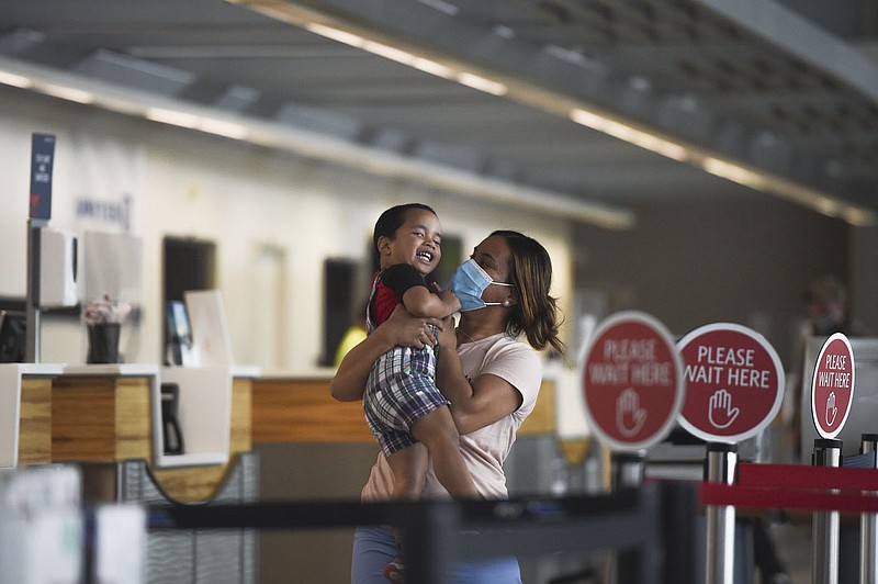 Emri Luther of Springdale (right) carries her son Ishmael Luther, 2, as she waits to have her luggage checked, Thursday, April 15, 2021 at the Northwest Arkansas National Airport in Bentonville. A year after passenger traffic at Northwest Arkansas National Airport dropped by 95% due to the covid-19 pandemic, airport officials say vaccines and pent up demand are likely to make for a busy summer travel season. Check out nwaonline.com/210418Daily/ for today's photo gallery. 
(NWA Democrat-Gazette/Charlie Kaijo)