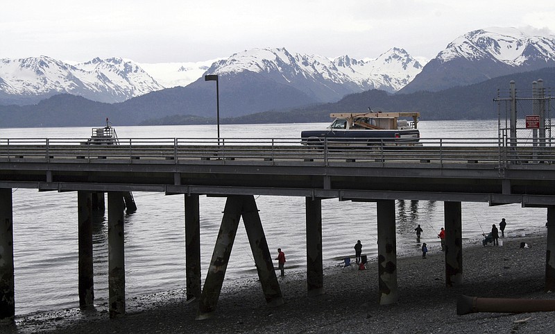 FILE - In this May 24, 2015, file photo, a vehicle drives on a pier to be loaded onto an Alaska state ferry while people fish underneath the pier in Homer, Alaska. The U.S. Supreme Court will hear oral arguments Monday, April 19, 2021, in a case that will determine who is eligible to receive more than $530 million in federal virus relief funding set aside for tribes more than a year ago. More than a dozen Native American tribes sued the U.S. Treasury Department to keep the money out of the hands of Alaska Native corporations, which provide services to Alaska Natives but do not have a government-to-government relationship with the United States. (AP Photo/Mark Thiessen, File)