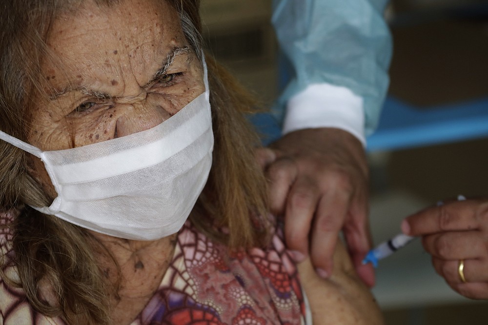 FILE - In this Feb. 18, 2021, file photo, a senior receives her second dose of China's Sinovac CoronaVac vaccine, during a priority vaccination program for the elderly at the Bezerra de Menezes Asylum in Brasilia, Brazil. The global death toll from the coronavirus topped a staggering 3 million people Saturday, April 17, 2021, amid repeated setbacks in the worldwide vaccination campaign and a deepening crisis in places such as Brazil, India and France. (AP Photo/Eraldo Peres, File)