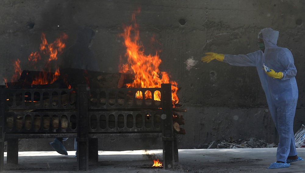 FILE - In this April 15, 2021, file photo, a municipal worker in personal protective suit performs last rites during the cremation of a COVID-19 victim in Vasai, outskirts of Mumbai, India. The global death toll from the coronavirus topped a staggering 3 million people Saturday, April 17, 2021, amid repeated setbacks in the worldwide vaccination campaign and a deepening crisis in places such as Brazil, India and France. (AP Photo/Rafiq Maqbool, File)