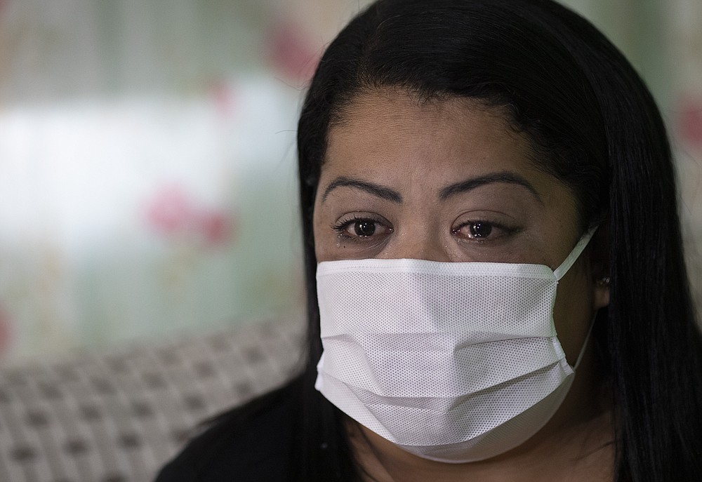 Nurse Lidiane Melo cries during an interview with The Associated Press at her home in Rio de Janeiro, Brazil, Wednesday, April 14, 2021. In the early days of the pandemic, as sufferers were calling out for comfort that she was too busy to provide, Melo filled two rubber gloves with warm water, knotted them shut, and sandwiched them around a patient's hand, to re-create a loving clasp. Some have christened the practice the "hand of God," and it is now the searing image of a nation roiled by a medical emergency with no end in sight. (AP Photo/Silvia Izquierdo)