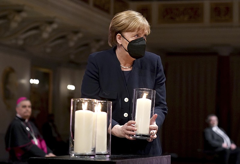 German Chancellor Angela Merkel holds a candle during a memorial service in Berlin, Germany, Sunday, April 18, 2021 in remembrance of Germany's corona dead. (AP Photo/Michael Sohn, pool)