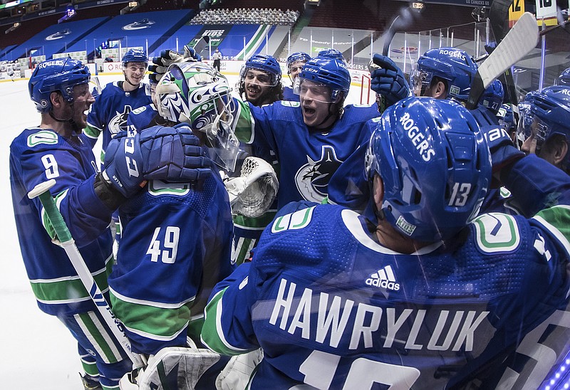 Vancouver Canucks' J.T. Miller (9), goalie Braden Holtby (49) and Brock Boeser (6) celebrate with teammates after the winning goal during overtime of an NHL hockey game against the Toronto Maple Leafs in Vancouver, British Columbia, Sunday, April 18, 2021. (Darryl Dyck/The Canadian Press via AP)