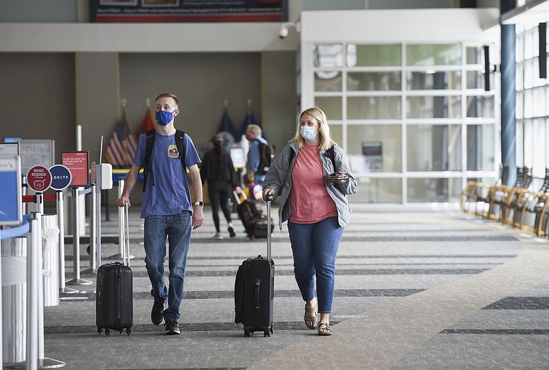 Joey Hall of Pea Ridge (from left) and Jessica Hall walk through the terminal, Thursday, April 15, 2021 at the Northwest Arkansas National Airport in Bentonville. A year after passenger traffic at Northwest Arkansas National Airport dropped by 95% due to the covid-19 pandemic, airport officials say vaccines and pent up demand are likely to make for a busy summer travel season. Check out nwaonline.com/210418Daily/ for today's photo gallery. 
(NWA Democrat-Gazette/Charlie Kaijo)