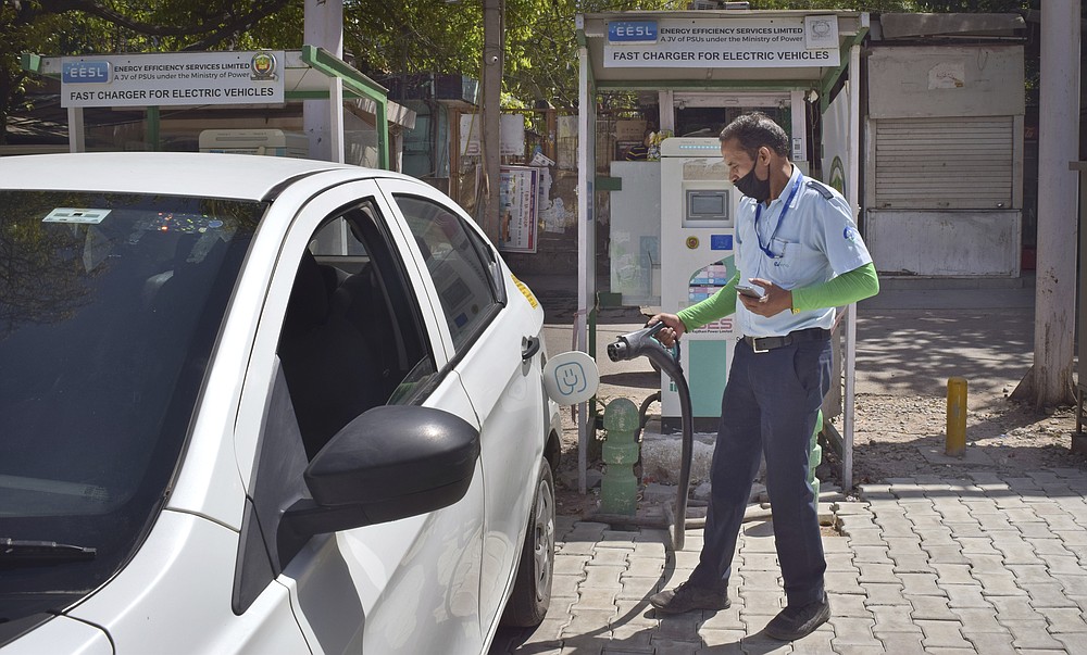 A driver of an electric car charges his vehicle at public charging station in New Delhi, India, Thursday, April 1, 2021. India has ambitions to expand use of electric vehicles to wean itself from polluting fossil fuels, but EVs are still a rarity on its congested highways. A lack of charging stations and poor quality batteries are discouraging drivers from switching over. (AP Photo/Neha Mehrotra)