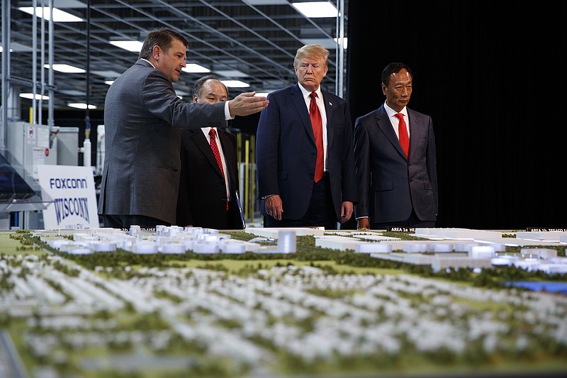 FILE - In this June 28, 2018 photo, President Donald Trump takes a tour of Foxconn with Foxconn chairman Terry Gou, right, and CEO of SoftBank Masayoshi Son in Mt. Pleasant, Wis. Foxconn Technology Group, the world's largest electronics manufacturer, has reached a new deal with reduced tax breaks for its scaled back project in southeast Wisconsin, Gov. Tony Evers and the the company announced on Monday, April 19, 2021. (AP Photo/Evan Vucci, File)