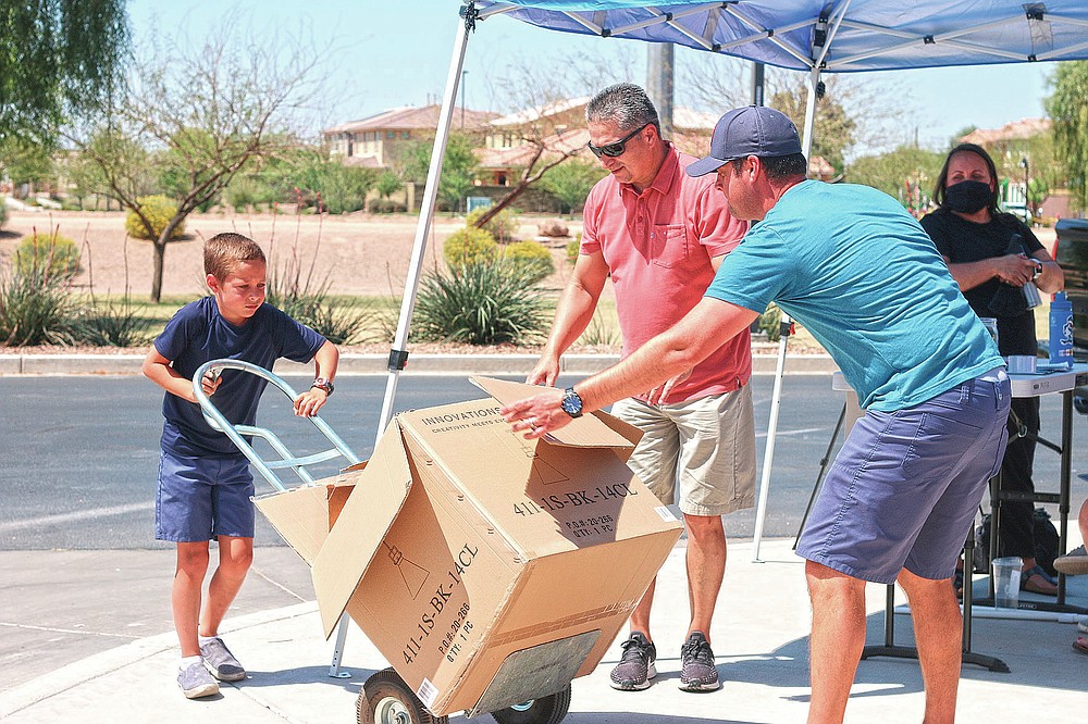 Dylan Pfeifer uses a lift to move a box filled with donated canned and boxed foods to his home in Chandler, Ariz., Saturday, April 3, 2021, to safely store the items until they are given to St. Mary's Food Bank. Pfeifer hosted his third food drive since October in response to the coronavirus pandemic. He collected about $450. (AP Photo/Cheyanne Mumphrey)