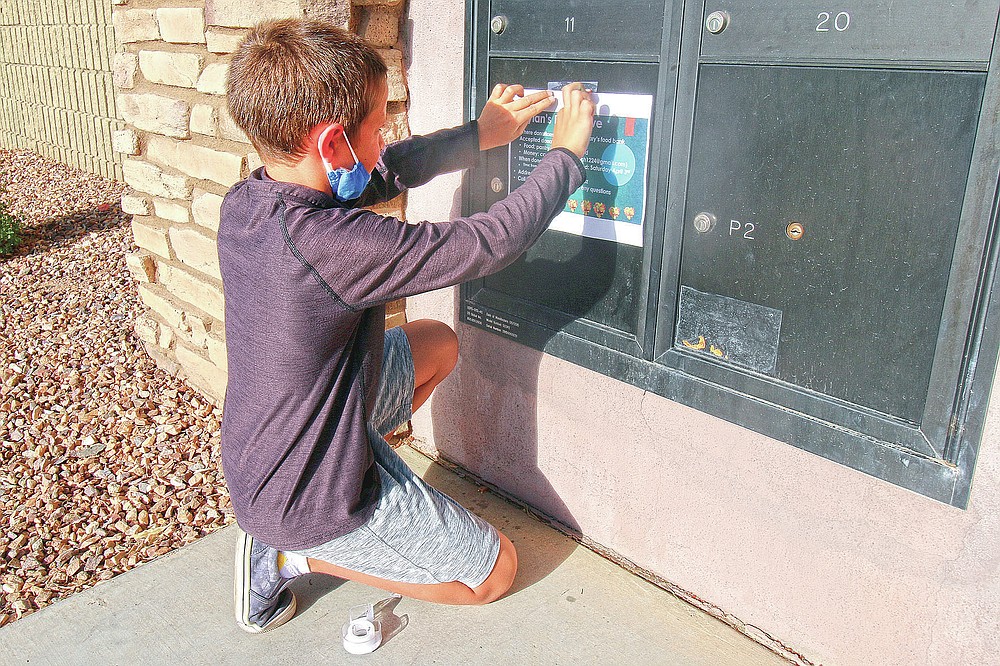 Dylan Pfeifer, 8, tapes up flyers in his neighborhood in Chandler, Ariz. on Thursday, April 1, 2021. The flyers promoted his third food drive since October in response to the coronavirus pandemic. (AP Photo/Cheyanne Mumphrey)