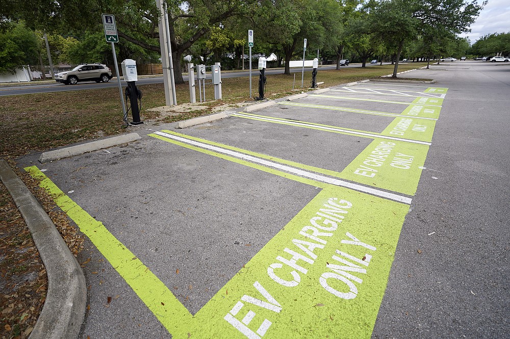A parking area with charging stations for electric vehicles at a public park is seen Thursday, April 1, 2021, in Orlando, Fla. As part of an infrastructure proposal by the Biden administration, $174 billion will be set aside to build 500,000 electric vehicle charging stations, electrify 20% of school buses and electrify the federal fleet, including U.S. Postal Service vehicles.(AP Photo/John Raoux)