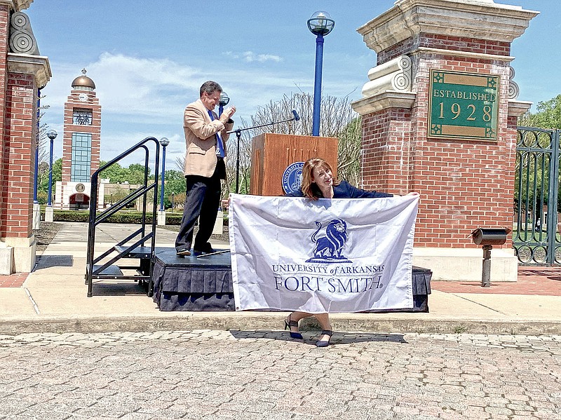 Terisa Riley, chancellor of the University of Arkansas - Fort Smith, displays the new UAFS flag while Chris Kelly, director of marketing and communications for the university, applauds behind her during the launch of the new UAFS brand at the university Wednesday. 
(NWA Democrat-Gazette/Thomas Saccente)