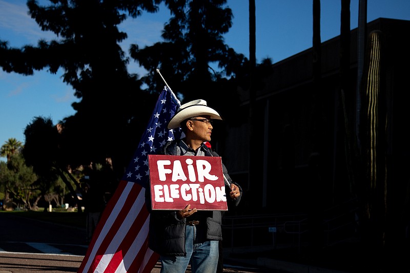 A protester stands outside the State Capitol Executive Tower in Phoenix on Dec. 14, the same day that Arizona's presidential electors met to cast their ballots. MUST CREDIT: Photo for The Washington Post by Courtney Pedroza