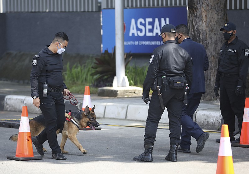 A member of Presidential Security Forces leads a sniffer dog at a check point outside the Association of Southeast Asian Nations (ASEAN) Secretariat ahead of a leaders' meeting in Jakarta, Indonesia, Saturday, April 24, 2021. Southeast Asian leaders are to meet Myanmar's top general and coup leader in an emergency summit in Indonesia Saturday, and are expected to press calls for an end to violence by security forces that has left hundreds of protesters dead as well as the release of Aung San Suu Kyi and other political detainees. (AP Photo/Dita Alangkara)