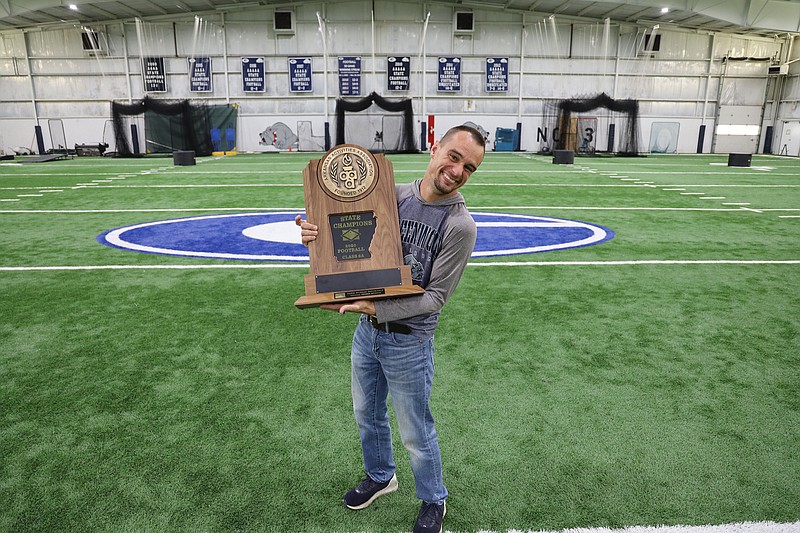 Jamie Freeman holds the Greenwood High School Bulldogs' 2020 Class 6A state champion trophy on the training field in the football complex he maintains as a school custodian.
(Special to the Democrat-Gazette/Dwain Hebda)