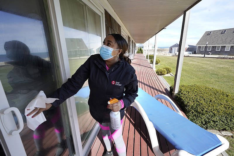 Worker Jennifer Porter, of Hyannis, Mass., cleans windows, Tuesday, April 6, 2021, at Red Jacket Resorts, in Yarmouth, Mass. Hotels, restaurants and other businesses in tourist destinations are warning that hiring challenges during the coronavirus pandemic could force them to pare back operating hours or curtail services just as they’re eyeing a bounce-back summer. (AP Photo/Steven Senne)