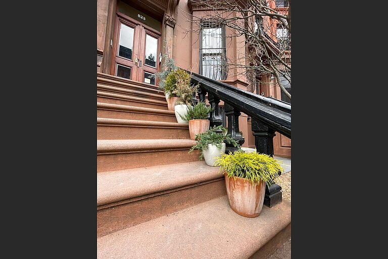 A procession of conifers in sturdy pots provide a welcoming guide up the stairs to the stoop of this brownstone in the Brooklyn borough of New York. (Kate Cook via AP)