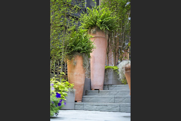 Tall terra cotta planters add a ‘wow’ factor to this stoop, with landscaping design by Janice Parker. (Neil Landino Jr./Janice Parker Landscape Architects via AP)