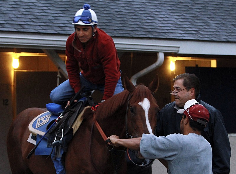 FILE - In this April 27, 2010, file photo, trainer John Sadler, upper right, watches as jockey Rafael Bejarano mounts a horse before a workout at Churchill Downs in Louisville, Ky. California-based Sadler is not necessarily supportive of horse racing’s move toward the elimination of race-day medication. Sadler saddles Rock Your World in this weekend’s Kentucky Derby, which will be run for the first time without horses using the anti-bleeding drug Lasix. (AP Photo/Garry Jones, File)