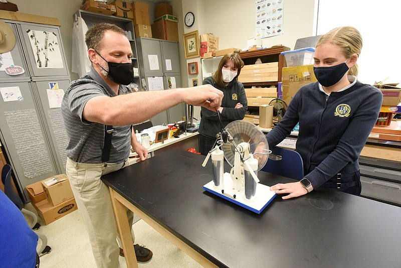 Chemistry teacher Pete Golden and student Carissa Kennedy (right) show on Tuesday April 27 2021 at Haas Hall Academy in Bentonville how a Wimshurst machine produces electric current and a spark that detours around obstacles such as a plastic spoon. Go to nwaonline.com/210428Daily/ to see more photos.
(NWA Democrat-Gazette/Flip Putthoff)