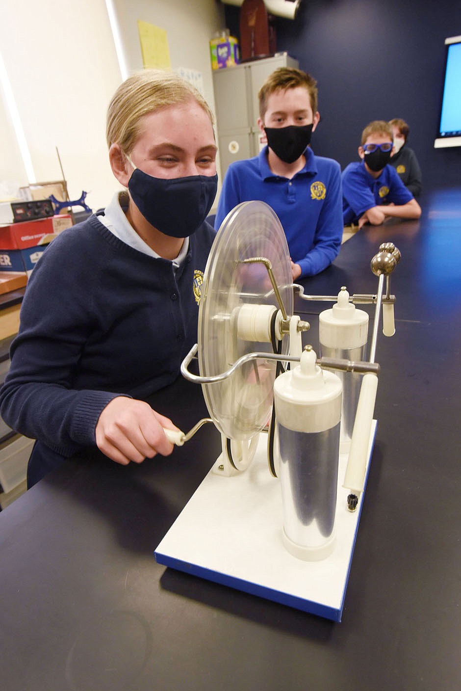 Carissa Kennedy, a student at Haas Hall Academy Bentonville, cranks a Wimshurst machine on Tuesday April 27 2021 to show how it produces electric current and sparks. Go to nwaonline.com/210428Daily/ to see more photos.
(NWA Democrat-Gazette/Flip Putthoff)
