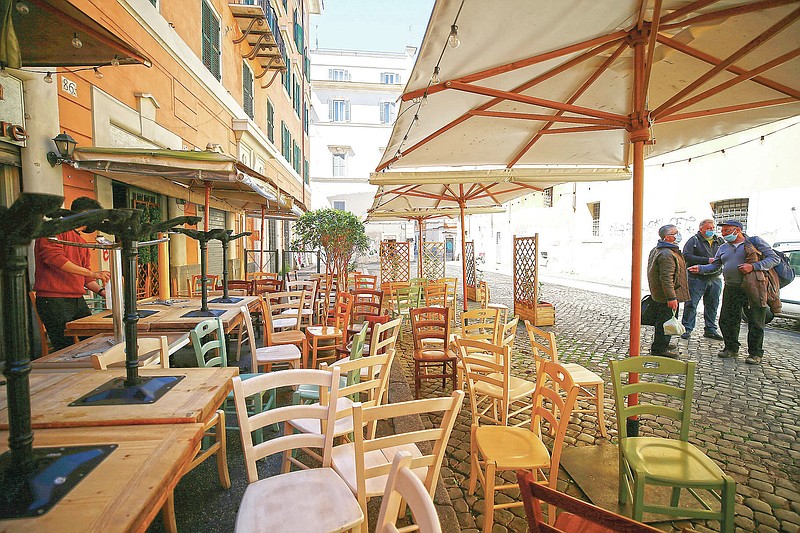 Chairs and tables are being prepared outside a restaurant ahead of Monday's reopening following the ease of COVID-19 restrictions, in Rome, Friday, April 23, 2021. Even Italy’s tentative reopening is satisfying no one. Outdoor dining is too little, too late for restaurant owners whose survival is threatened by a year of rotating closures. Yet the nation’s weary virologists worry that Monday, April 26, 2021, will see people crowding bars and restaurants and bring yet another spike to the virus that has not really properly receded yet. (Cecilia Fabiano/LaPresse via AP)