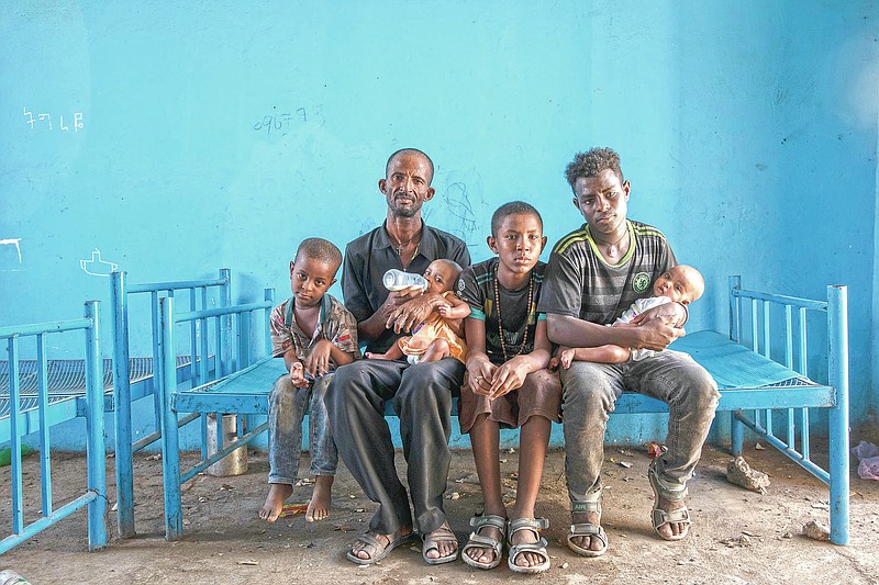 Tigrayan refugee Abraha Kinfe Gebremariam, 40, second left, sits for a photograph with his sons, Micheale, 5, left; Daniel, 11, center; his 19-year-old brother-in-law, Goytom Tsegay, second right, and his 4-month-old twin daughters Aden, right, and Turfu Gebremariam, on his lap, inside their family's shelter in Hamdayet, eastern Sudan, near the border with Ethiopia, on March 23, 2021. A fellow refugee, Mulu Gebrencheal, a mother of five, has become an informal adviser, offering guidance on the babies’ care. Abraha and his sons are quick learners, she said. But she mourns for the twins and the death of their mother. “Even the hug of a mother is very sweet,” she said. “They’ve never had this. They never will.” (AP Photo/Nariman El-Mofty)