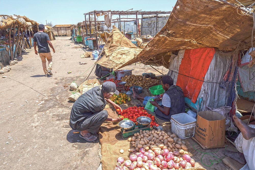 Tigrayan refugee Abraha Kinfe Gebremariam, 40, buys tomatoes at the market in Hamdayet, eastern Sudan, near the border with Ethiopia, on March 21, 2021. One day during the conflict in his home village, his son, Daniel, tried to visit the market and saw some 10 bodies being piled onto a vehicle for burial. He saw another four bodies in the dirt. Daniel never went to the market again. (AP Photo/Nariman El-Mofty)
