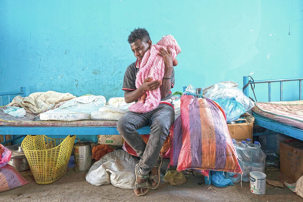 Tigrayan 19-year-old refugee Goytom Tsegay, tries to comfort his 4-month-old niece, Turfu Gebremariam, inside their family's shelter in Hamdayet, eastern Sudan, near the border with Ethiopia, on March 21, 2021. “I spend the whole day with them. ... My favorite part is feeding them. I’ve decided to stay with them all their lives.” (AP Photo/Nariman El-Mofty)