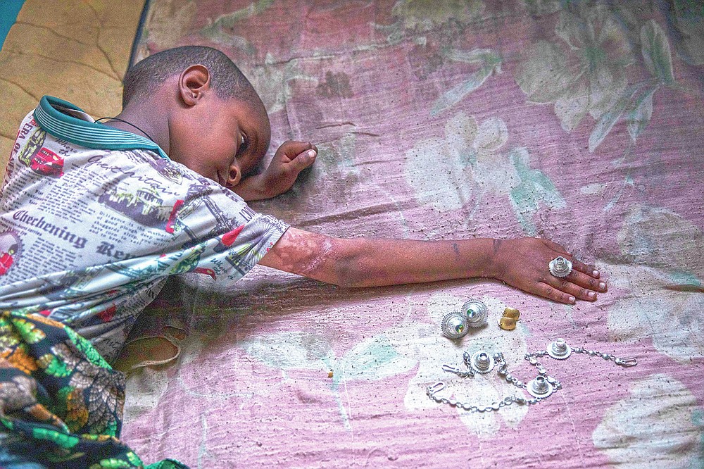Tigrayan 5-year-old refugee Micheale Gebremariam plays with jewelry belonging to his deceased mother, Letay, inside the family's shelter in Hamdayet, eastern Sudan, near the border with Ethiopia, on March 14, 2021. (AP Photo/Nariman El-Mofty)
