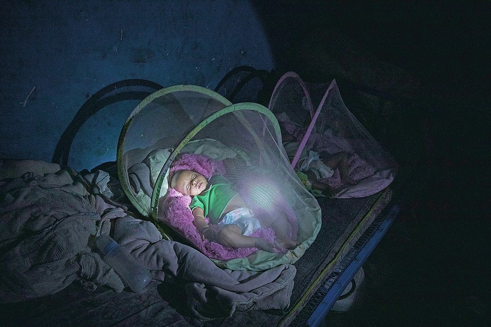 Tigrayan refugee Abraha Kinfe Gebremariam, 40, uses a flashlight to check on his 4-month-old twin daughters, Aden and Turfu, after praying at a church early in the morning, in Hamdayet, eastern Sudan, near the border with Ethiopia, on March 21, 2021. Even as Tigrayans ran for their lives or jostled for space on a boat to safety, the sight of the tall, silent, sorrowful man carrying the tiny twin girls made people pause. (AP Photo/Nariman El-Mofty)