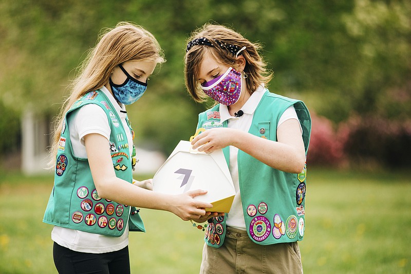 In this April 14, 2021 image provided by Wing LLC., from left, Girl Scouts, Alice and Gracie pose with a Wing delivery drone container in Christiansburg, Va. The company is testing drone delivery of Girl Scout cookies in the area. (Sam Dean/ Wing LLC. via AP)
