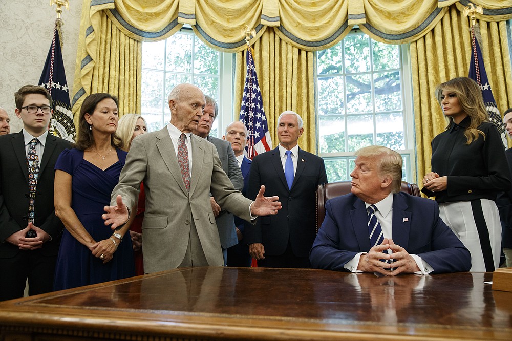 FILE - In this Friday, July 19, 2019 file photo, President Donald Trump listens to Apollo 11 astronauts Michael Collins, third from left, with Vice President Mike Pence and first lady Melania Trump, during a photo opportunity commemorating the 50th anniversary of the Apollo 11 moon landing, in the Oval Office of the White House in Washington. Collins, who piloted the ship from which Neil Armstrong and Buzz Aldrin left to make their historic first steps on the moon in 1969, died Wednesday, April 28, 2021, of cancer, his family said. He was 90. (AP Photo/Alex Brandon)