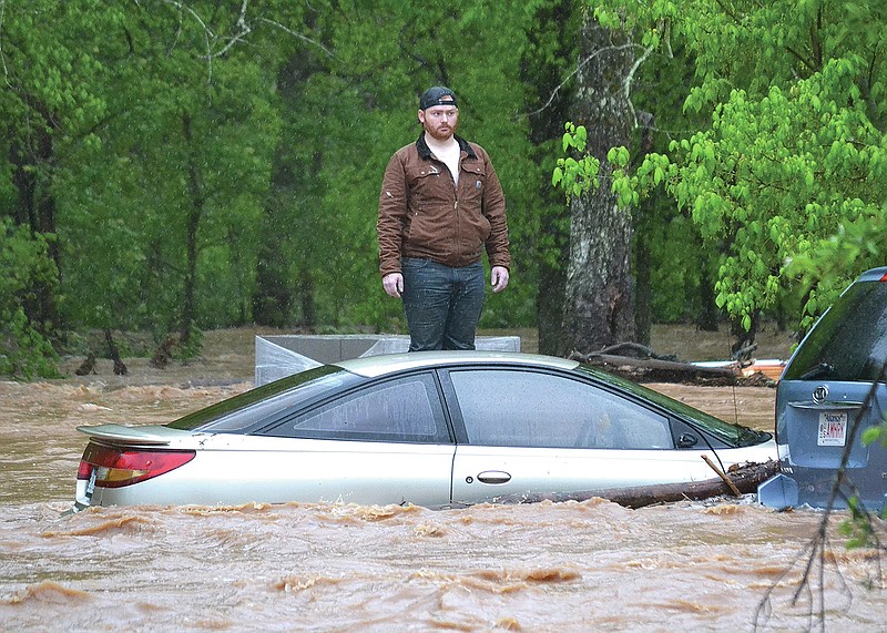 Jaxon Douglass, 21, waits patiently for water rescue personnel to reach him as he stands on concrete blocks outside his grandparents' home on Rustic Drive Wednesday morning. His uncle was swept away in the water and was also rescued safely.
(Pea Ridge Times/Annette Beard)