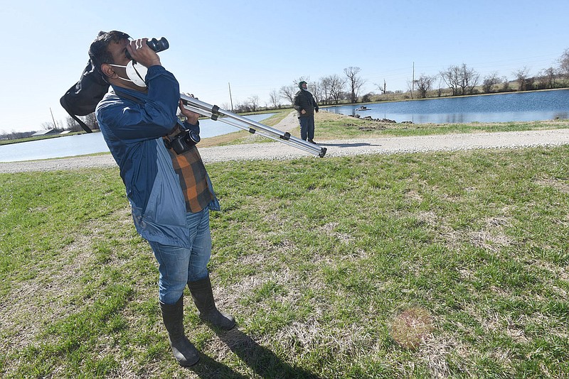 Vivek Govind Kumar (left) and Joe Neal look at birds in March 2021 at the state fish hatchery.
(NWA Democrat-Gazette/Flip Putthoff)