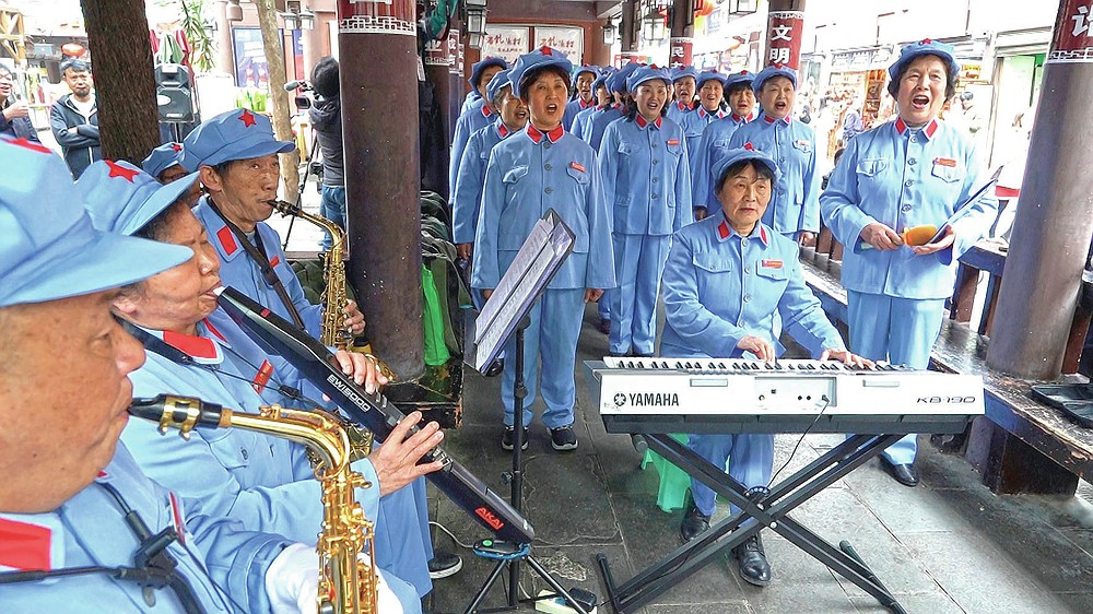 A group of local retirees gathers in Zunyi City, southwest China's Guizhou Province, to sing revolutionary Red Army songs on April 12, 2021.  The group, whose members are in their late 50s to over 80 years old, gather regularly to sing tourists visiting the nearby Zunyi Memorial Museum.  The late communist leader Mao Zedong rose to power in the museum located on the site of the Zunyi conference.  (AP Photo / Emily Wang)