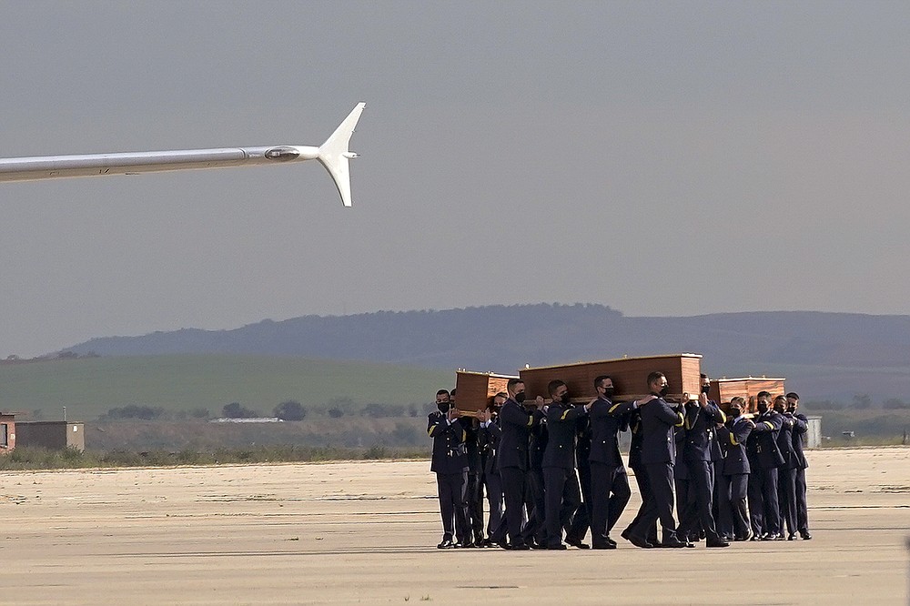 Coffins carrying the bodies of Spanish reporters David Beriain, Roberto Fraile and the director of the Chengeta Wildlife Foundation Rory Young, arrive from Burkina Faso at the Madrid military airport on Friday, April 30, 2021. Two Spanish journalists and the Irish director of a wildlife foundation were killed Monday in an ambush in eastern Burkina Faso. The two journalists were working with the wildlife campaigner on a documentary about poachers in a national park bordering Benin when they were attacked by gunmen. (AP Photo/Andrea Comas)