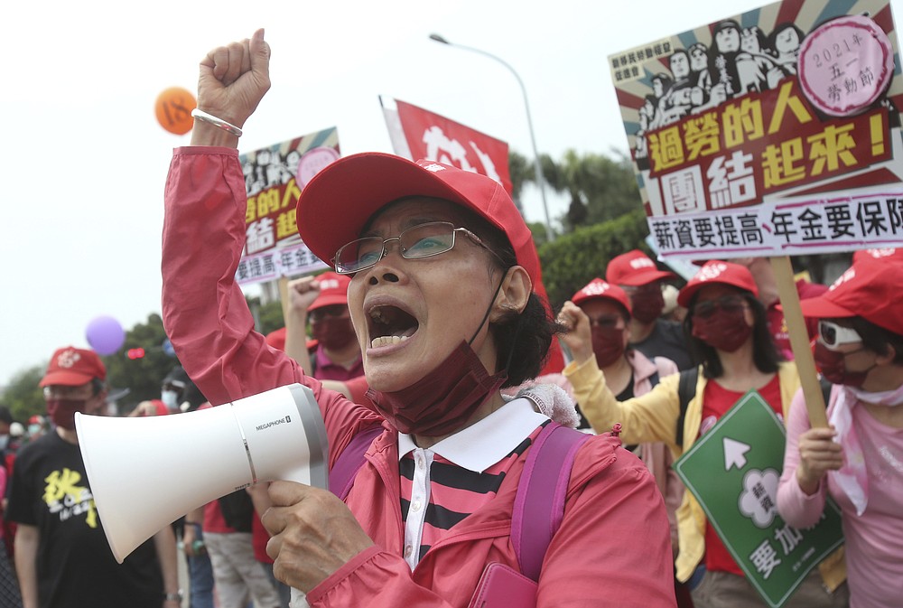 Taiwanese workers shout and hold slogans during a May Day rally in Taipei, Taiwan, Saturday, May 1, 2021. Thousands of protesters from different labor groups protest on the street to ask for increasing salary and securing annuity. (AP Photo/Chiang Ying-ying)